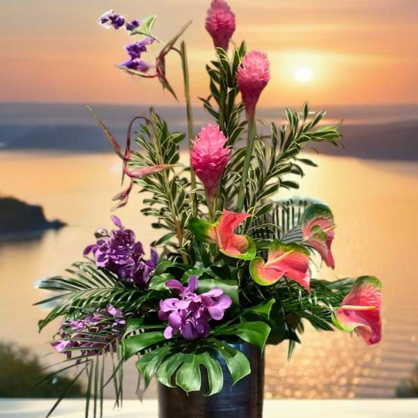 Tropical flower arrangement in a tall dark vase with pink and purple blooms