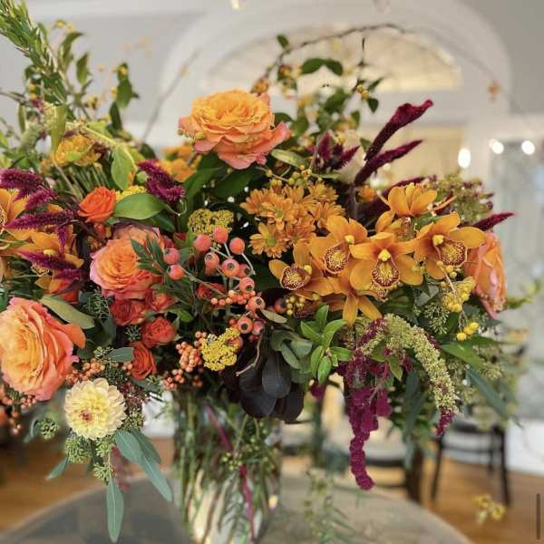 Mixed orange and purple floral arrangement in a clear glass vase