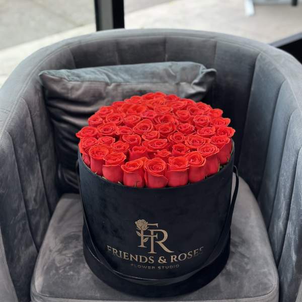 Round box of red roses on a gray chair