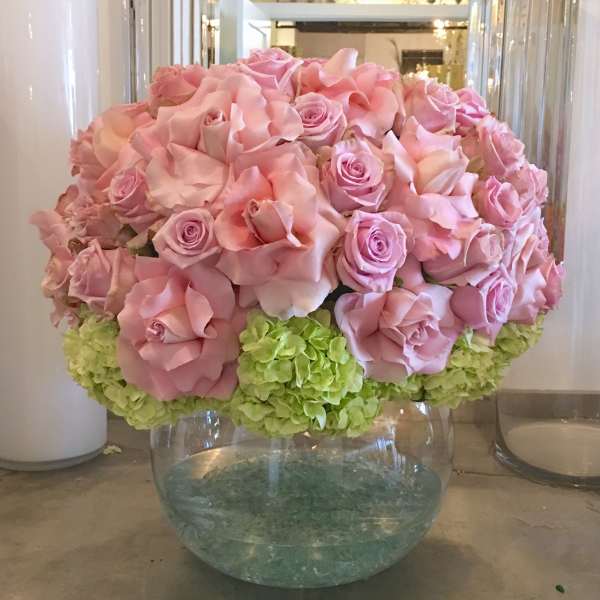 Low round arrangement of pink roses and green hydrangeas in a clear glass bowl vase