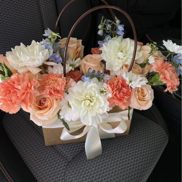 Peach roses and white dahlias in a gift basket with a ribbon