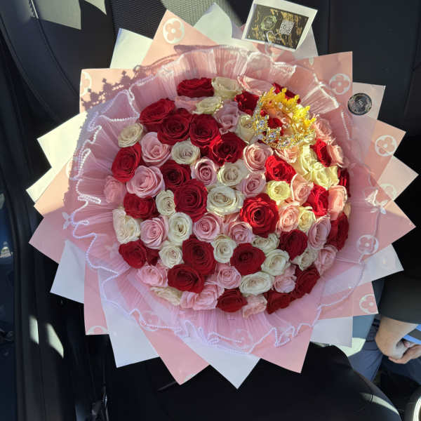 Large bouquet of red, pink, and white roses wrapped in pink paper