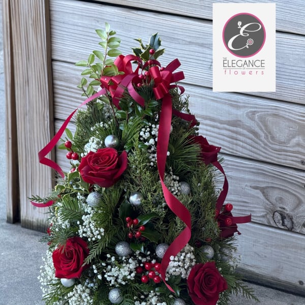 Christmas arrangement with red roses, ribbon, and ornaments in a wooden base
