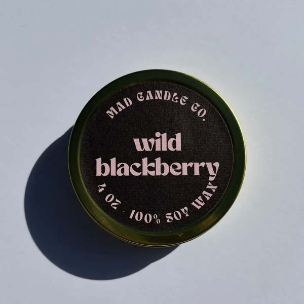 Round candle tin labeled wild blackberry on a light surface