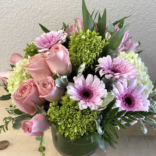 Pink roses and lavender daisies arranged in a green vase