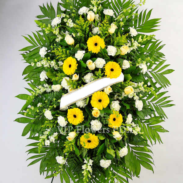 Standing funeral wreath of yellow and white flowers on an easel