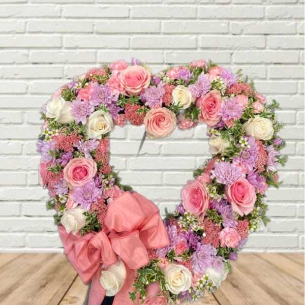 Heart-shaped floral wreath with pink and lavender roses and a large pink bow