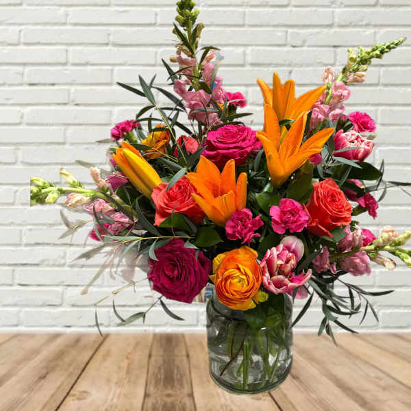 Bright mixed bouquet with orange lilies and pink roses in a glass vase