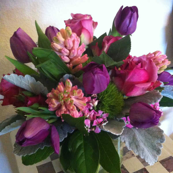 Bouquet of pink roses and purple tulips in a glass vase