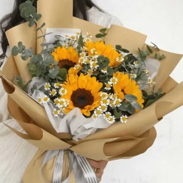 Bouquet of sunflowers and small white daisies wrapped in brown paper
