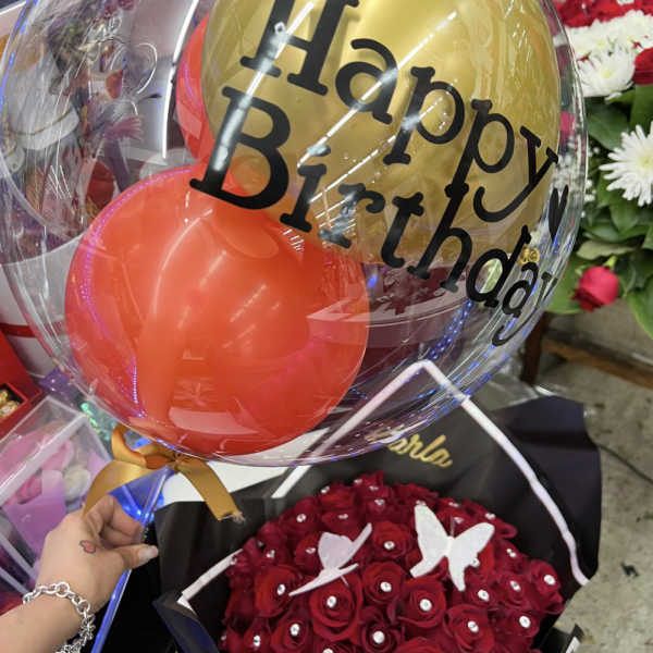 Birthday balloon bouquet with gold and red balloons over red roses