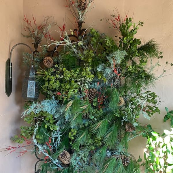 Large wall arrangement of pine, berries, and pinecones with a lantern