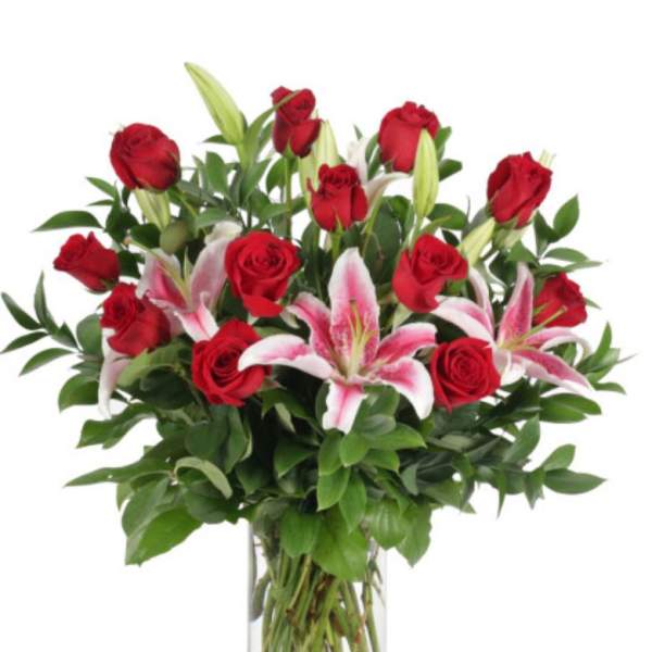 Red roses and pink lilies in a clear glass vase