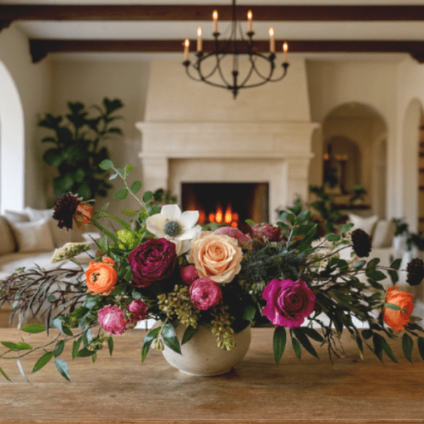 Mixed rose arrangement in a low ceramic vase on a wooden table