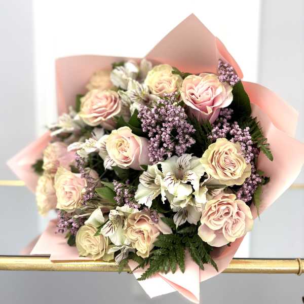 Bouquet of pale pink roses and white flowers wrapped in pink paper
