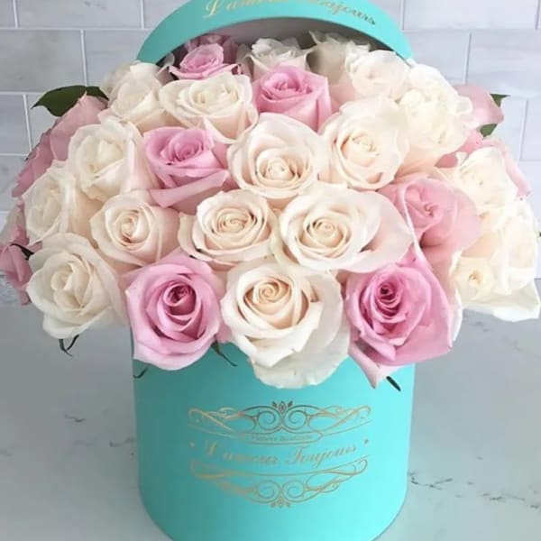 Pink and white roses arranged in a turquoise hat box