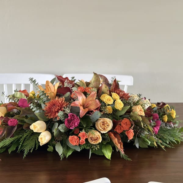 Low floral centerpiece with roses, lilies, and chrysanthemums in autumn colors