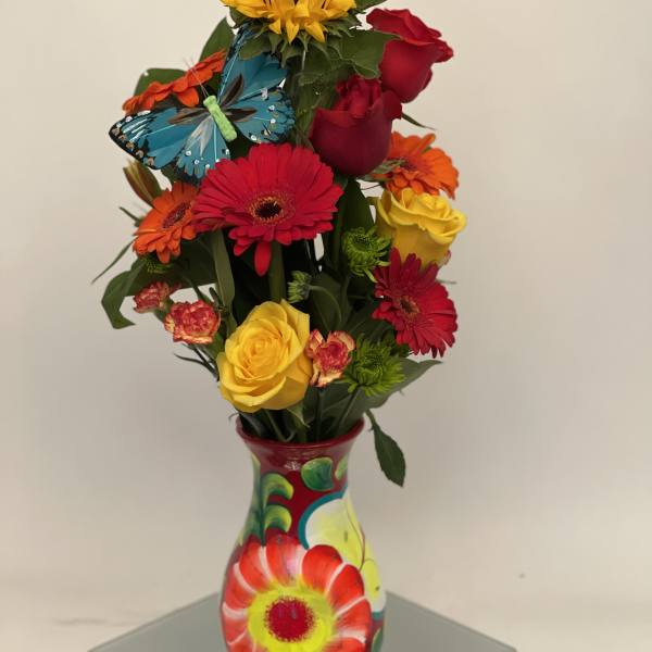 Colorful bouquet of roses, gerbera daisies, and a sunflower in a painted vase