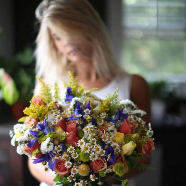 Woman holding a colorful bouquet of roses and daisies