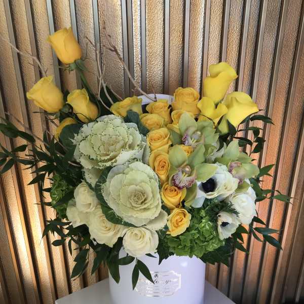 Yellow and white floral arrangement in a white hatbox