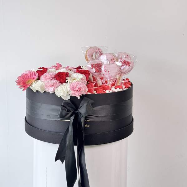 Black gift box with pink and white flowers and heart-shaped lollipops
