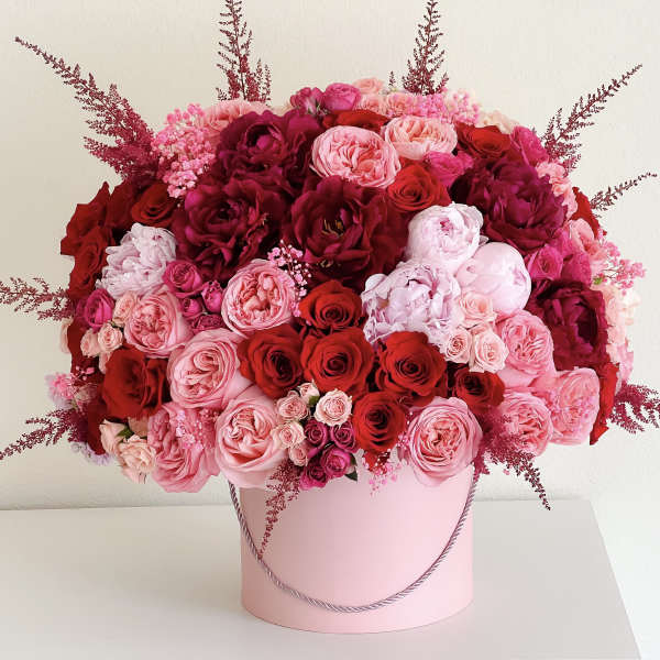 Large pink and red rose arrangement in a pink hatbox