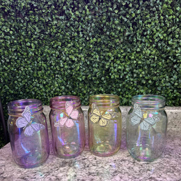 Four iridescent glass jars with butterfly decorations