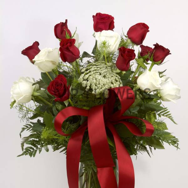 Red and white roses in a glass vase with a red ribbon