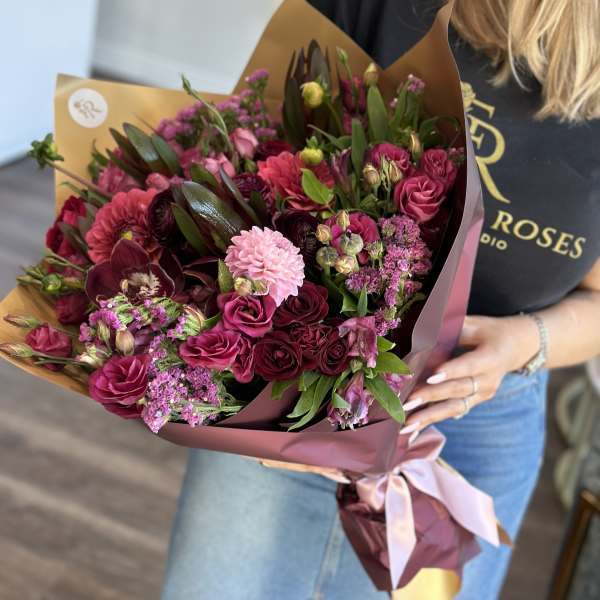 Bouquet of pink and burgundy flowers wrapped in mauve paper