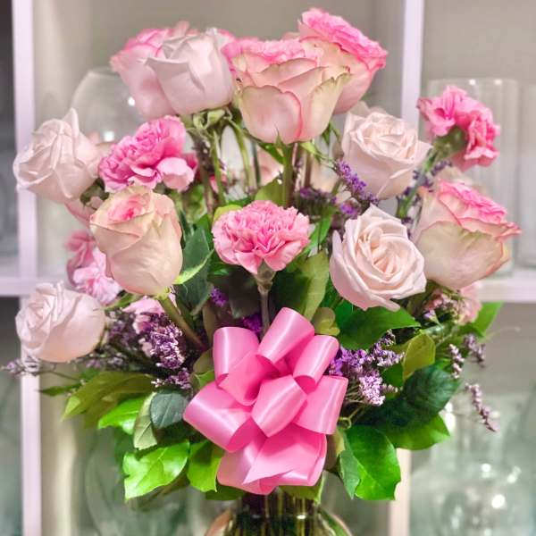 Pink roses and carnations in a glass vase with a pink ribbon