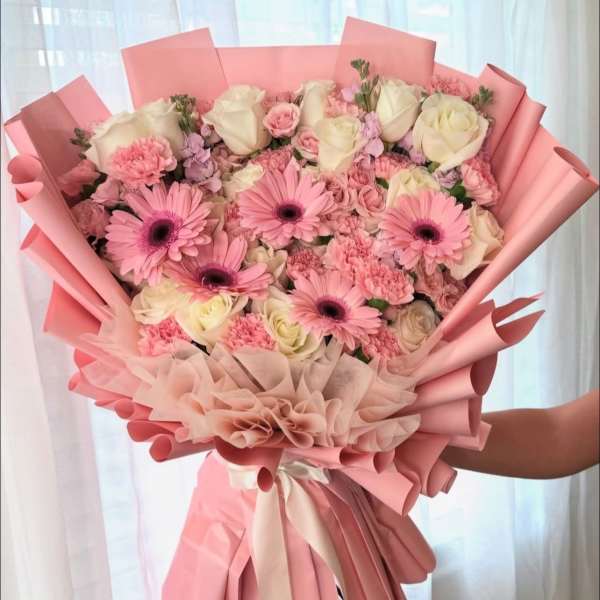 Large pink bouquet with roses, gerbera daisies, and carnations wrapped in pink paper