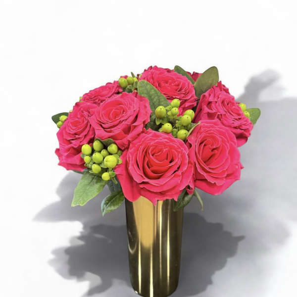 Pink roses arranged in a gold vase with green berry accents