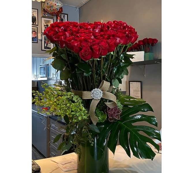 Large bouquet of red roses in a tall vase with a ribbon bow