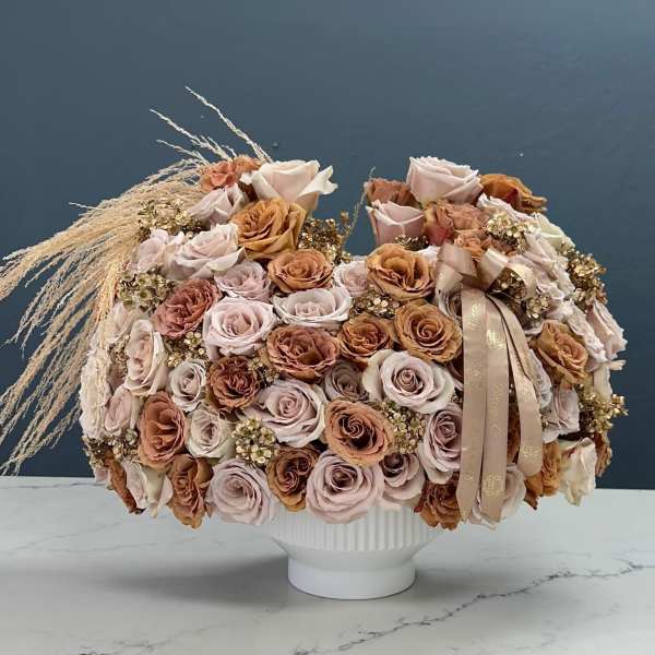 Large bouquet of pale roses in a white vase with a ribbon