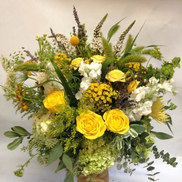 Yellow roses and white flowers in a burlap-wrapped vase