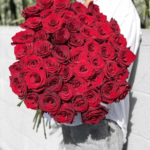 Large bouquet of red roses held by a woman outdoors