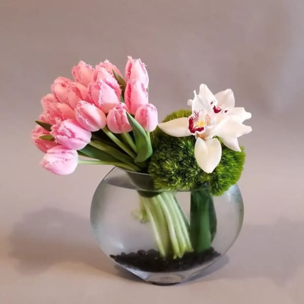 Round glass vase with pink fringe tulips, white orchids, and green pom-style blooms.