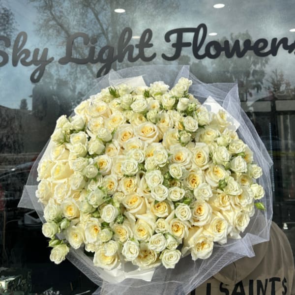 Large bouquet of cream and pale yellow roses wrapped in white tulle