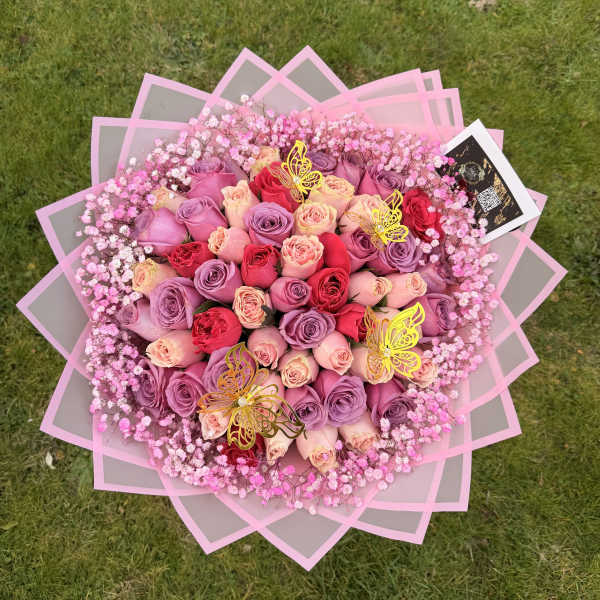 Large bouquet of pink, lavender, and red roses with baby’s breath
