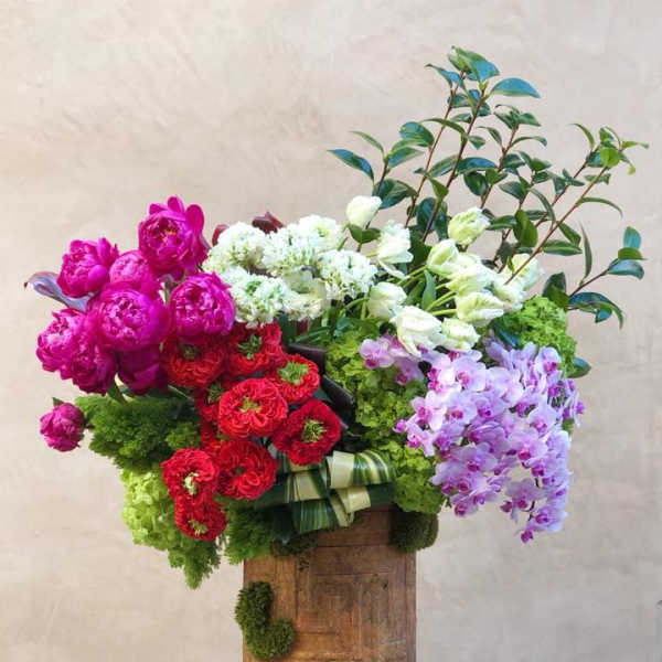 Large mixed bouquet with pink, red, white, and lavender flowers in a wooden container