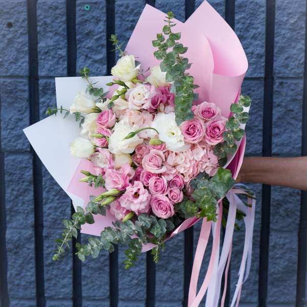 Pink and white bouquet of roses and lisianthus wrapped in pastel paper