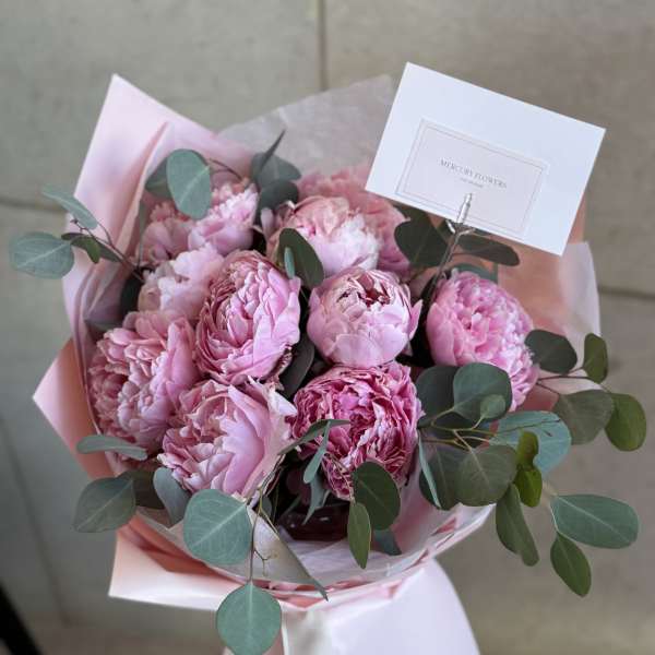 Pink peony bouquet with eucalyptus in pastel wrapping