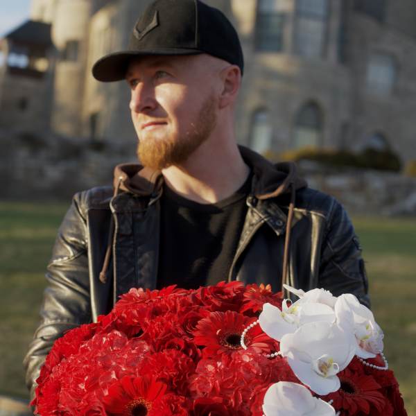 Large red floral arrangement in a black hatbox with white orchids and pearl strands