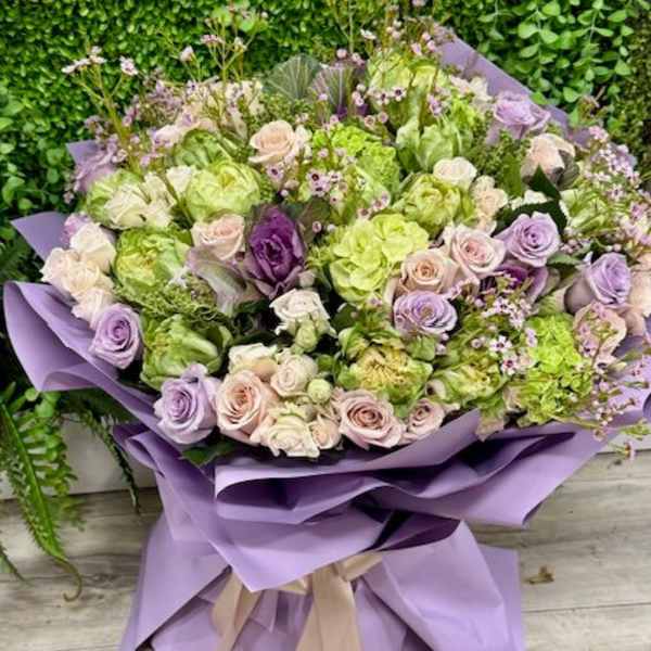 Lavender and green bouquet of roses wrapped in purple paper