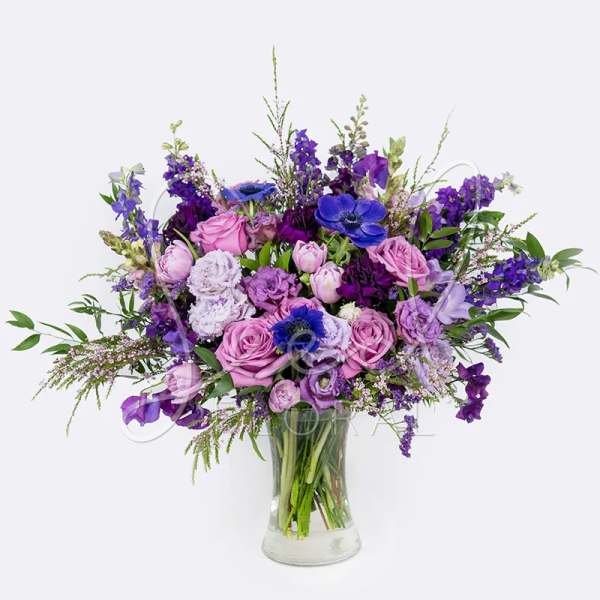 Purple and pink mixed bouquet in a clear glass vase