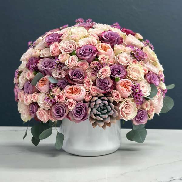 Round bouquet of pink and purple roses in a white vase