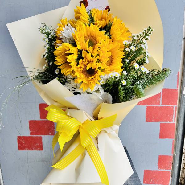 Bouquet of yellow sunflowers with white filler flowers in cream wrapping