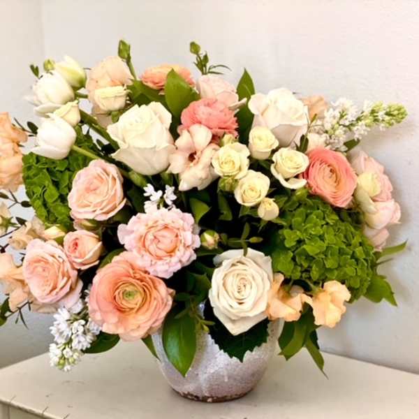 Large pastel bouquet of roses and ranunculus in a silver vase