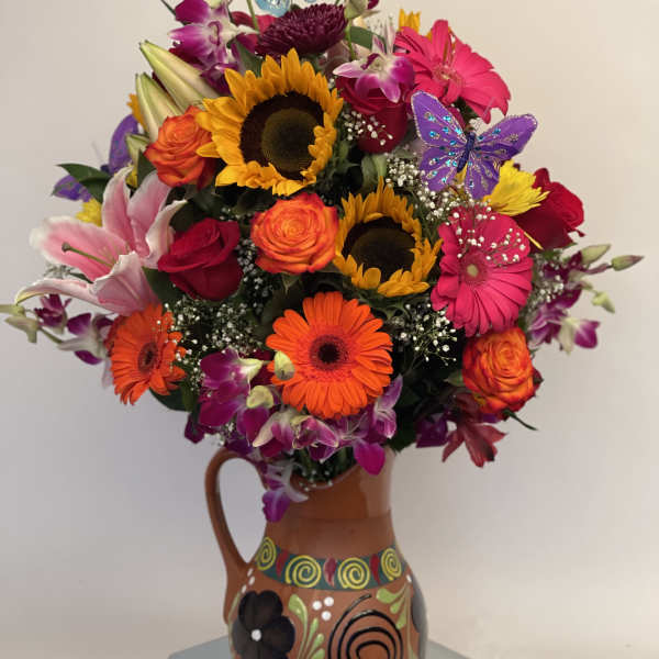 Colorful bouquet of sunflowers, roses, lilies, and gerbera daisies in a painted vase