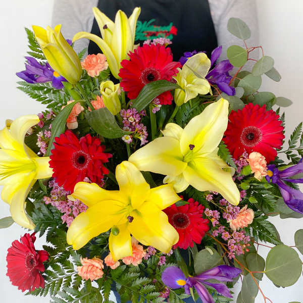 Bouquet of yellow lilies, red gerbera daisies, and purple flowers